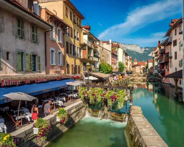 Canal animé à Annecy, avec des restaurants en terrasse et des fleurs colorées. Idéal pour découvrir les choses à faire à Annecy.