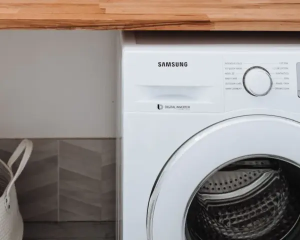 Biała pralka Samsung z technologią Digital Inverter. Obok kosz na pranie.