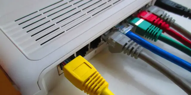Router z podłączonymi kolorowymi kablami sieciowymi.