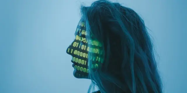 Profil kobiety z zielonym kodem binarnym na twarzy na niebieskim tle.