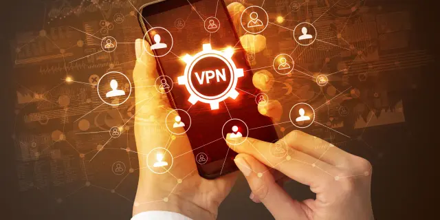 Dłonie trzymające smartfon z ikoną VPN i siecią połączeń użytkowników.