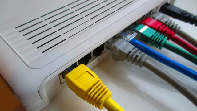 Router z podłączonymi kolorowymi kablami sieciowymi.