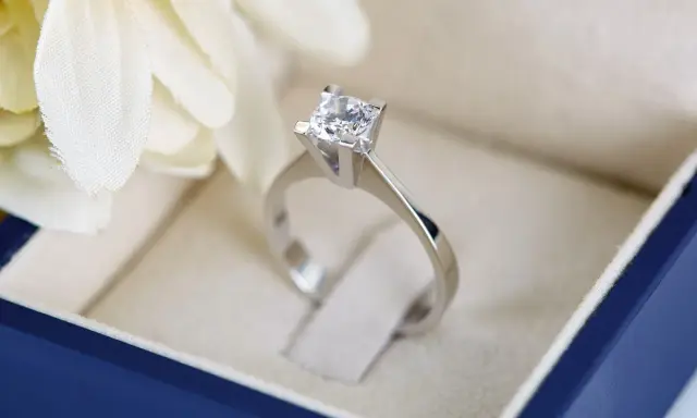 Anello con diamante solitario in un cofanetto blu, un simbolo di amore eterno. Il diamante gioielleria brilla.