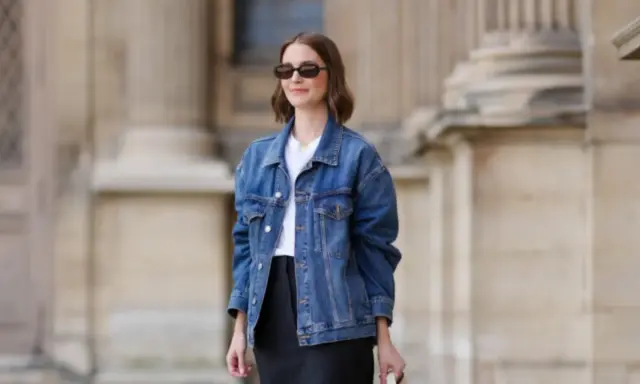 Donna con occhiali da sole indossa un outfit giacca jeans donna, t-shirt bianca e gonna nera.