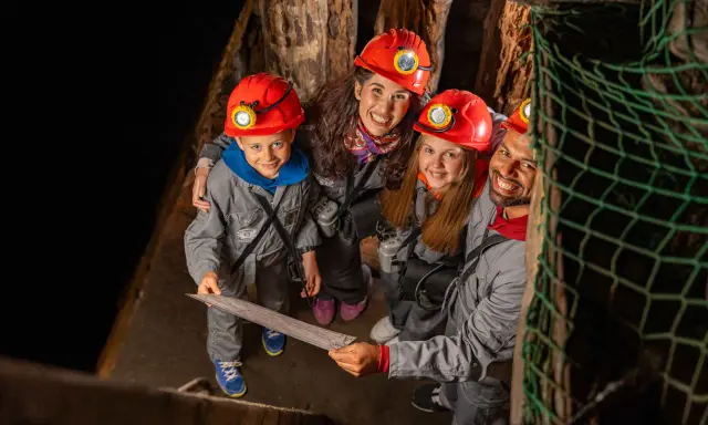 Rodzina w kaskach zwiedza kopalnię soli w Wieliczce. Dzieci z mapą w ręku, gotowe na przygodę!