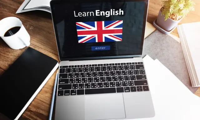 Laptop z napisem "Learn English" i flagą Wielkiej Brytanii. Obok kawa, notatnik i roślina. Idealne do nauki fce use of english.