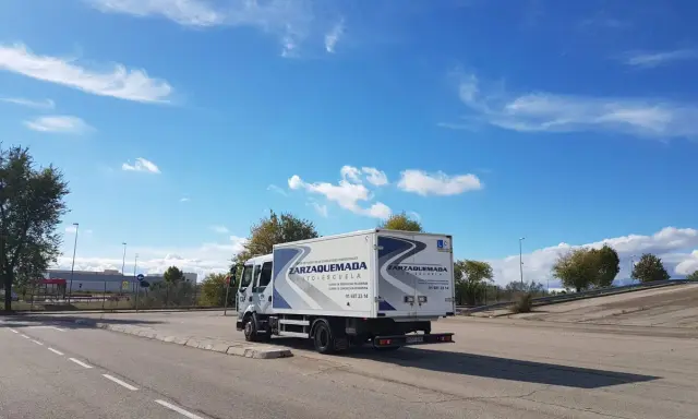 Camión de autoescuela Zarzaquemada, listo para obtener el carnet C+E. Cielo azul con nubes.