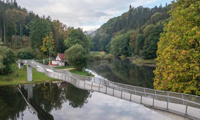 Idealna wycieczka na niedzielę na Dolny Śląsk: nowoczesny most nad spokojną rzeką, otoczony jesiennym lasem i wieżą widokową na wzgórzu.