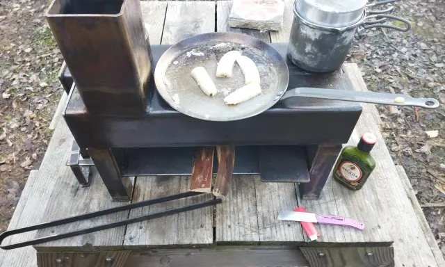 Poêle rocket fait maison, avec des bananes qui dorent dans une poêle, une marmite et une bouteille de rhum Negrita.