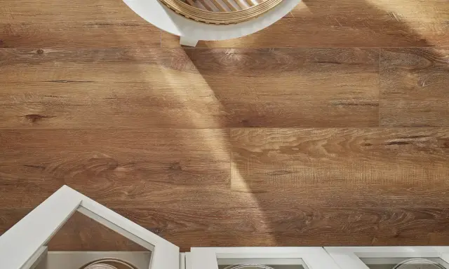 Drewnopodobne panele laminowane czy winylowe na podłodze, z fragmentem białej szafki i blatu.