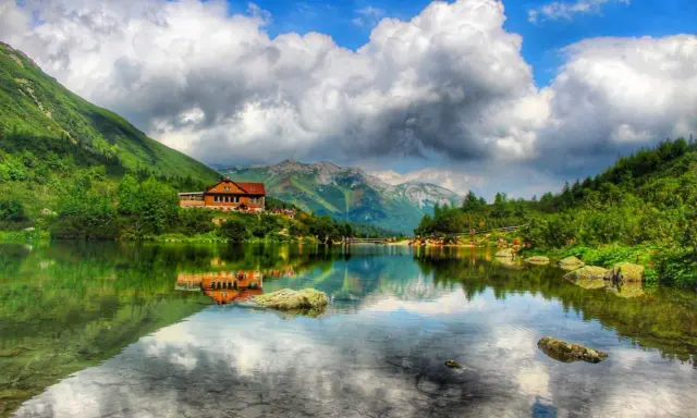Piękne tatry słowackie z dziećmi nad jeziorem. Chata odbija się w spokojnej tafli wody, a góry otaczają malowniczy krajobraz.