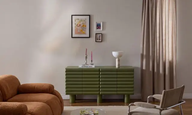 Un salotto moderno con divano color caramello, un mobile verde a coste e un gruppo di quadri appesi in modo originale.