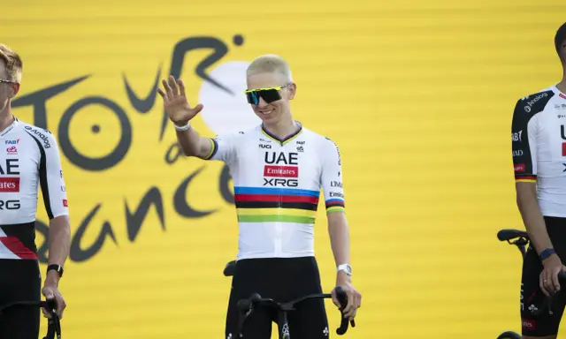 Radfahrer mit bunten Trikotfarben der Tour de France winkt fröhlich.