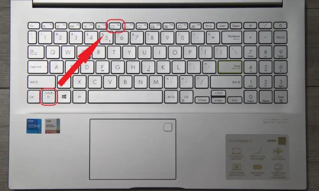 Klawiatura laptopa z podświetloną ikoną touchpada. Czerwona strzałka wskazuje klawisz Fn+Esc, który może aktywować touchpad.