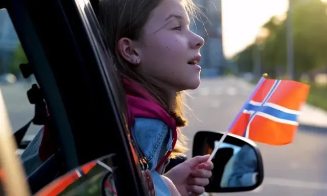 Dziewczynka z norweską flagą w ręku, wyjeżdża z kraju. Sprowadzenie auta z Norwegii to początek nowej przygody.