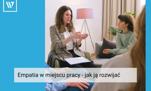 Kobieta w marynarce tłumaczy coś dłonią, siedząc naprzeciwko słuchaczy. Widać, że to rozmowa o empatii w pracy, która buduje lepsze relacje.