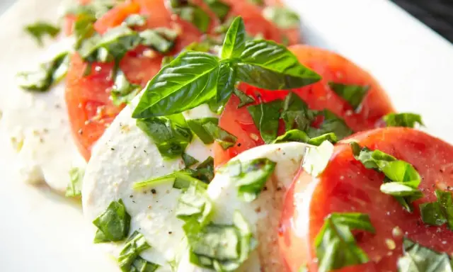 Salade Caprese : fines tranches de tomates rouges et de mozzarella crémeuse, parsemées de basilic frais. Une recette simple et savoureuse.