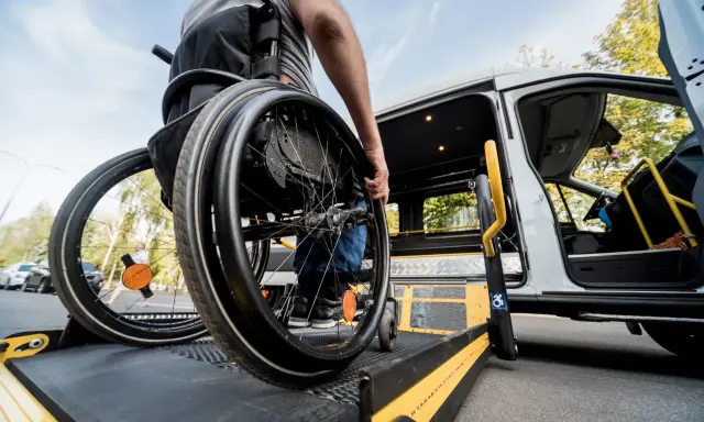 Osoba na wózku inwalidzkim wjeżdża na platformę windy. Dowiedz się, jak załatwić wózek inwalidzki i zapewnić sobie mobilność.