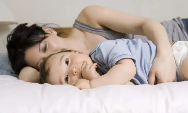 Mama tuli roczne dziecko do snu, przytulając je blisko.