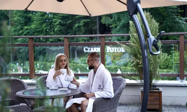 Para młoda w szlafrokach pije kawę na tarasie. Idealne miejsce na podróż poślubną w Polsce.