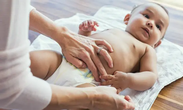 Mama sprawdza brzuszek maluszka, martwiąc się, że dziecko nie sika od 24 godzin.
