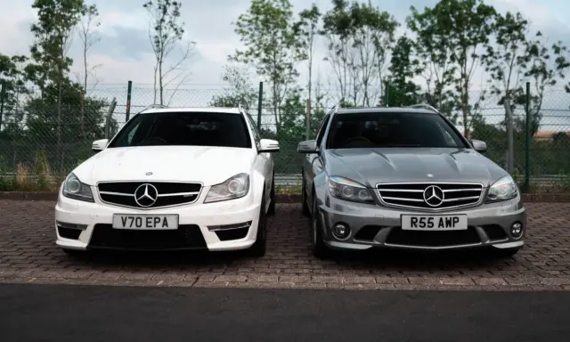 Dwa Mercedesy C63 AMG W204, biały i szary, stoją obok siebie na parkingu.