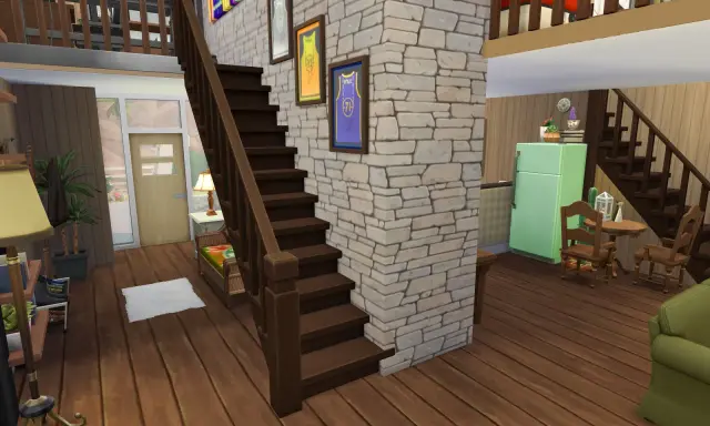 Wnętrze domu w The Sims 4: drewniane schody, kamienna ściana, lodówka i meble.