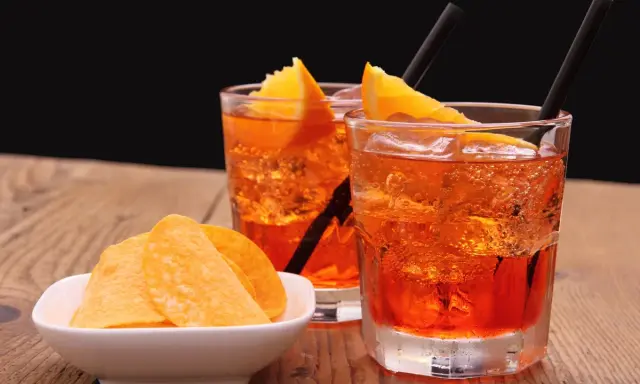 Dwa orzeźwiające drinki z pomarańczą i słone chipsy. Idealny aperitif, by rozpocząć wieczór.