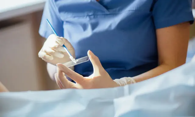 Lekarz w rękawiczkach przygotowuje preparat do badania cytologicznego, które pozwala wykryć zmiany w komórkach.