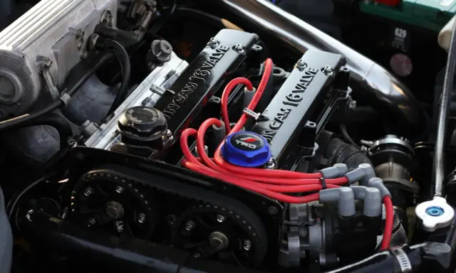 Motor de coche con tapa de válvulas "16 VALVE", cables rojos y correa de distribución.