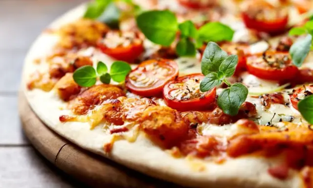 Pyszna pizza bez drożdży z pomidorkami koktajlowymi i świeżą bazylią, idealna na szybki obiad.