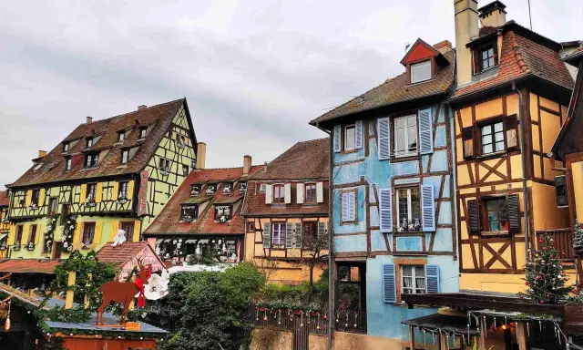 Case colorate e a graticcio lungo un canale, un'incantevole scena tra le città europee da visitare, con decorazioni natalizie.