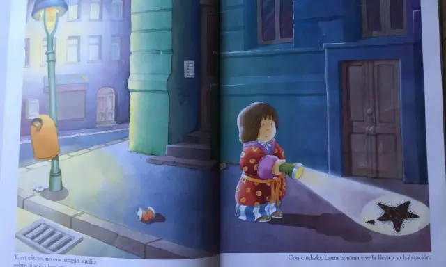 Laura, protagonista de "la estrella de laura cuento", ilumina con su linterna una estrella caída en la acera.