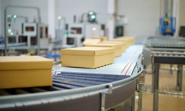 Pudełka na taśmie transportowej w magazynie ecommerce.