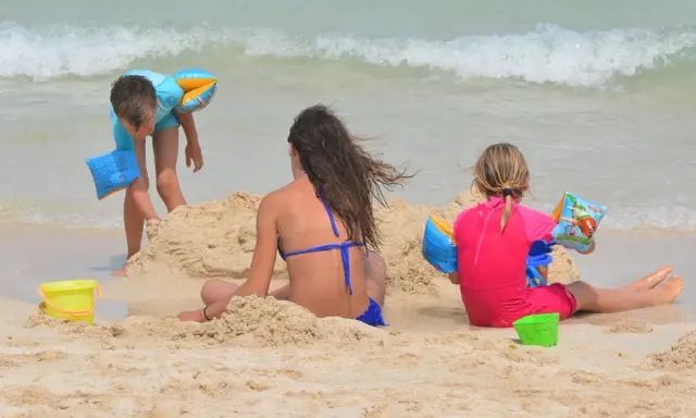 Bambini giocano sulla spiaggia, costruendo castelli di sabbia e godendosi il mare. Una giornata perfetta in una spiaggia per bambini.