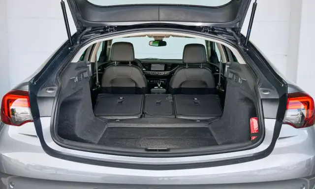 Maletero abierto de un Opel Insignia gris, mostrando asientos traseros abatidos y espacio de carga. Ideal para conocer las medidas del maletero.
