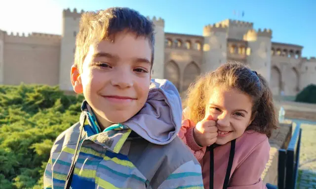 Dos niños sonríen frente al Palacio de la Aljafería, un lugar genial que ver en Zaragoza con niños.