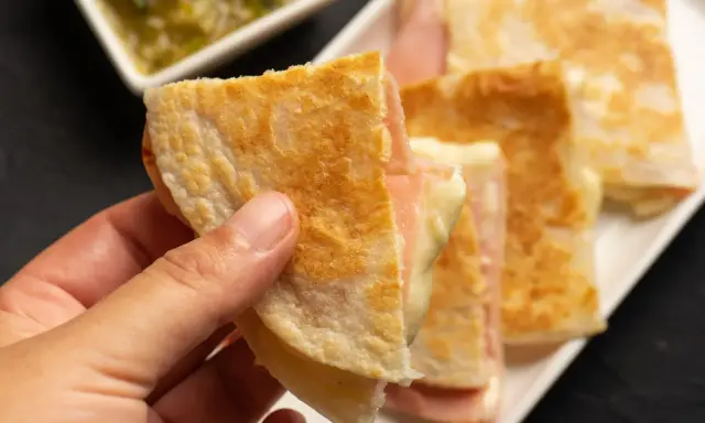 Ciepłe quesadille z szynką i serem, idealne na szybką kolację. Obok sos.