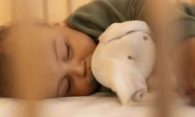 Dulce sueño de bebé de 6 meses, abrazando su peluche mientras duerme plácidamente en su cuna.