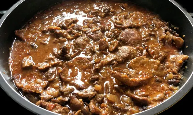 Fricandó de ternera cocinándose en una sartén, con trozos de carne tierna en una salsa espesa y aromática.