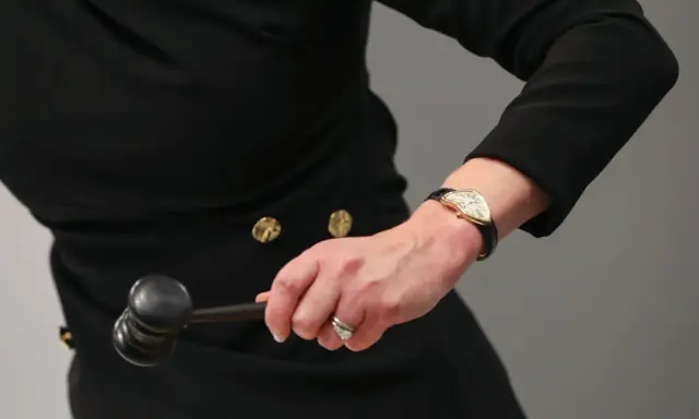 Auctioneer's hand with a gavel, ready to finalize an art loan.