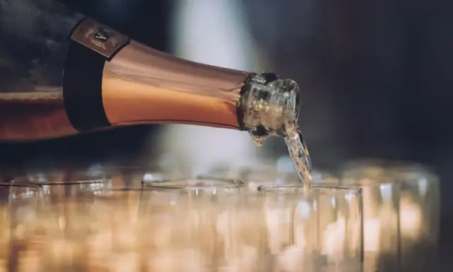 En flaska hälls upp i glas, det ser ut att bli gott bubbel.