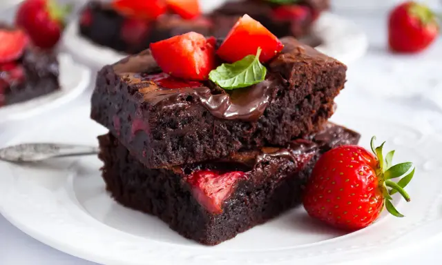 Pyszne brownie z truskawkami, polane czekoladą i ozdobione świeżymi owocami. Idealne na deser!