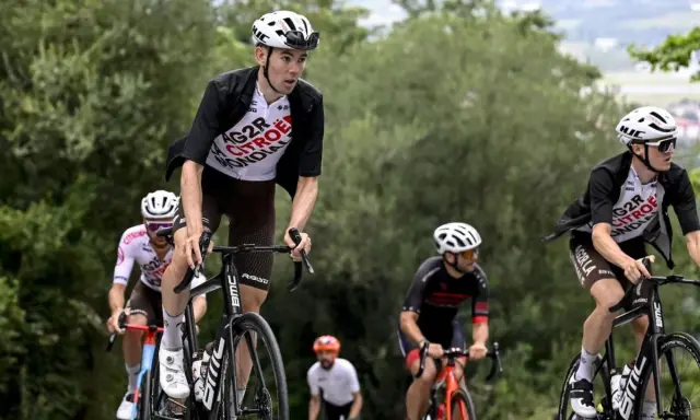 Radfahrer im Rennen bei der Dauphiné Rundfahrt. Ein Fahrer in weißem Trikot mit "AG2R CITROEN" Aufschrift fährt bergauf.