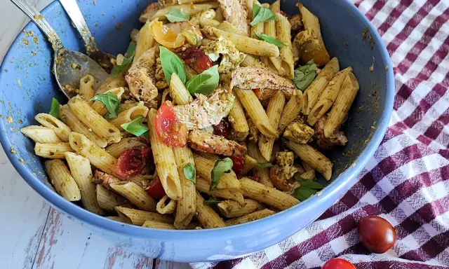 Un plat généreux de penne à la salade pesto, garni de poulet effiloché, tomates cerises et basilic frais. Un délice pour les papilles !