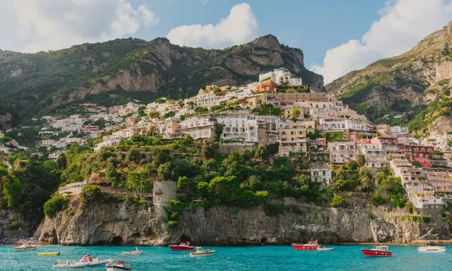 Positano, un gioiello da scoprire, perfetto per chi cerca cosa vedere a Napoli in un giorno. Case colorate aggrappate alla scogliera, mare azzurro e barche.