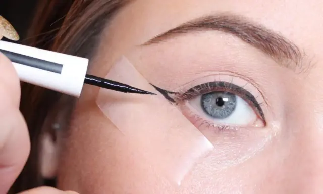 Aplicando delineador con cinta para aprender como hacer la raya del ojo para principiantes. Ojo azul, ceja definida, delineador negro.