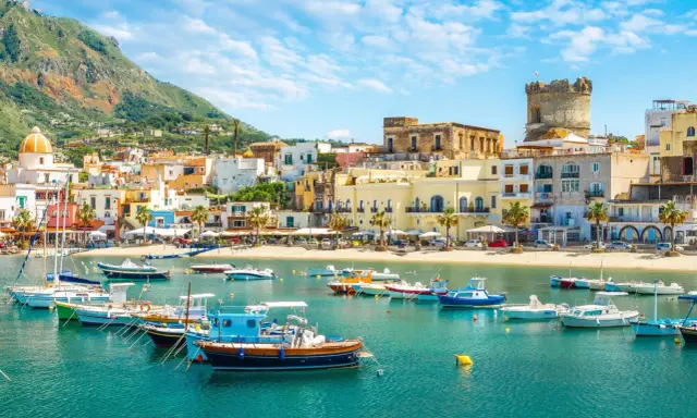 Un incantevole scorcio di Ischia con bambini che sognano gite in barca. Case colorate, mare azzurro e un castello medievale.