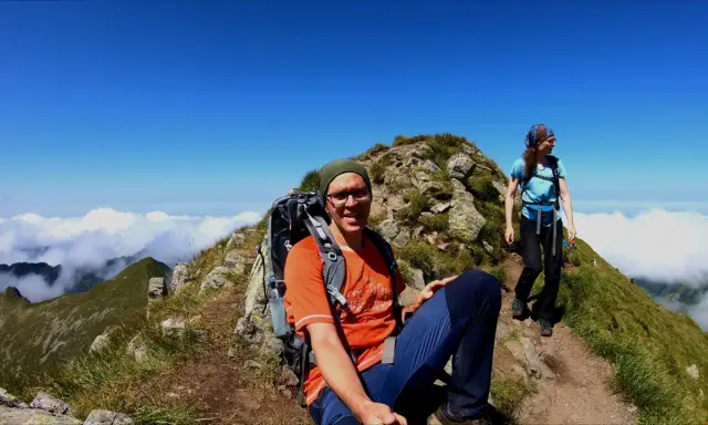 Dwoje turystów w górach, na tle błękitnego nieba i chmur.