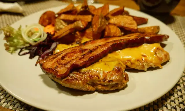 Pyszny burger z bekonem i serem, podany z frytkami i surówką. Smakuje jak w bacówce u Józka w Łodzi!